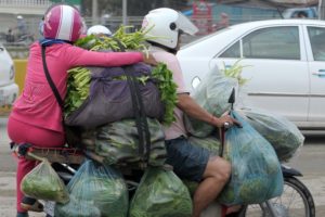 A Cambodian man rides his motorbike loaded with vegetables travelling along a street in Phnom Penh on July 6, 2016. / AFP PHOTO / TANG CHHIN SOTHY