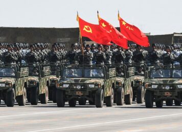 ทหารจีนพร้อมธงพรรคคอมมิวนิสต์ รัฐ และกองทัพปลดปล่อยประชาชน ระหว่างการสวนสนามที่ฐานซ้อมรบ Zhurihe เมื่อ 30 ก.ค. 2017 (ภาพจาก AFP)